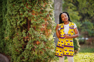 Stylish african american women in yellow jacket posed on street with hot drink in disposable paper cup.