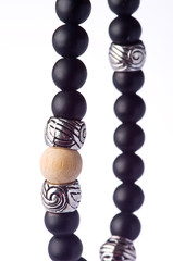 Closeup of a bracelet of black onyx pearls with tibetan metal spacer on a white background
