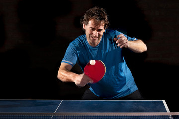 Deportista jugando tenis de mesa sobre fondo negro.	