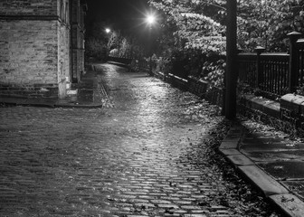 The lamp lit cobbled streets of Saltaire, pictured in moody black & white, reveal while this street is often used by film companies for location shots