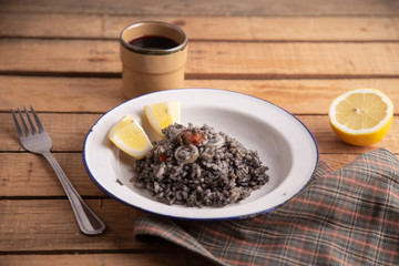 Plate of black rice with squid and prawns or Valencian black paella