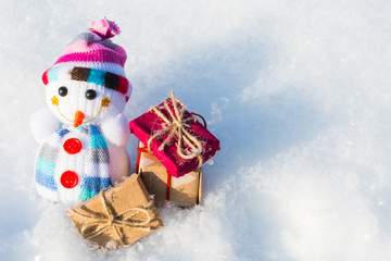 toy snowman with gifts in the snow