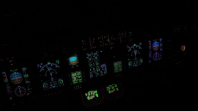 Illuminated instruments and avionics of an aircraft flight deck in a pitch black cockpit.