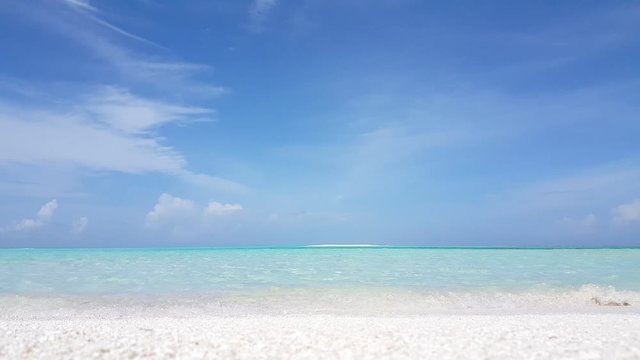 White sand beach with small waves from light blue ocean, exotic horizon and blue sky. no camera movement