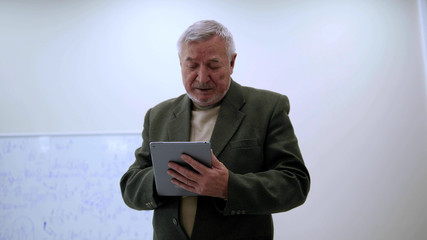 Professor in jacket work with tablet and sigh.