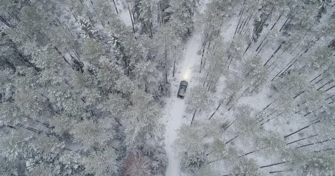 4x4 car driving in winter forest, top-down aerial drone shot