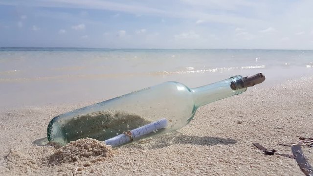 Vintage message in bottle coming from the sea on white sandy beach in Thailand, copy text