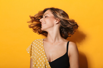 Photo of happy young woman wearing dress smiling and waving her hair