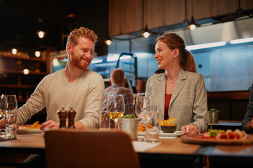 Group of friends sitting in retaurant and eating dinner.