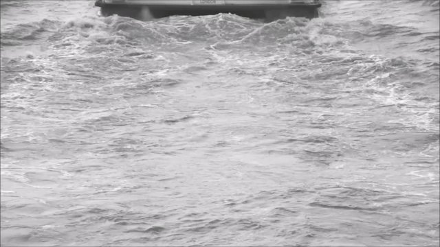 A clipper boat ride on the River Thames, London, UK, seen from the very rear where the engines propel the passenger boat through the water.
