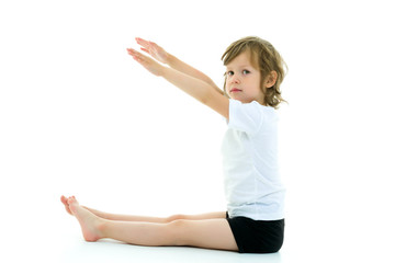 Charming little girl doing gymnastic exercises in the studio on