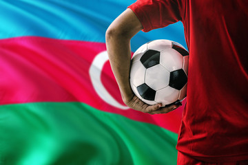 Azerbaijan national football team and player holding soccer ball against blurred flag background....