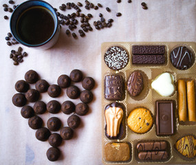 Set of sweets, cookies, coffee, chocolate truffles in a wooden box. on the table, coffee beans in the shape of a heart. a romantic gift for Valentine's day.