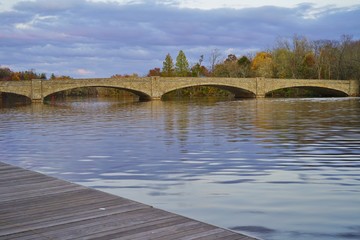 Fototapeta na wymiar Fall foliage over the Washington Road Bridge on Lake Carnegie in Princeton, New Jersey