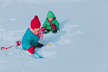 little girls play in winter, kids dig snow, seasonal activities