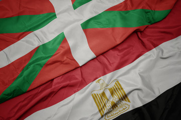 waving colorful flag of egypt and national flag of basque country.