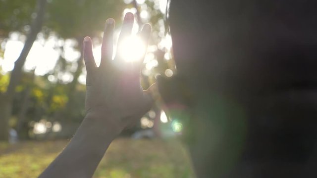 Black man protecting his face from sun with hand in the park-back view