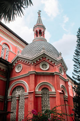 Close up of Tan Dinh church exterior with steeple and red wall against the blue sky in Ho Chi Minh city, Vietnam