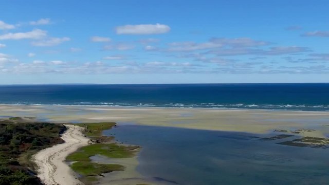 Peaceful drone footage of an idyllic dune road along a breathtaking New England beach on Cape Cod in the summer.