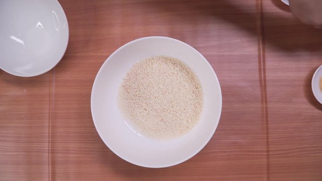 Putting breadcrumbs and spices into white bowl