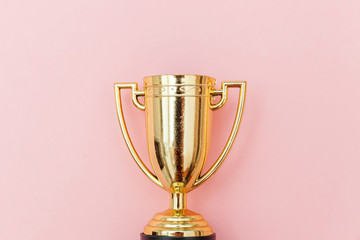 Simply flat lay design winner or champion gold trophy cup isolated on pink pastel colorful background. Victory first place of competition. Winning or success concept. Top view copy space