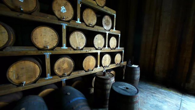 A barrier of whiskey barrels tapped for tasting with a bottle and snifter of whiskey on top of a standing cask
