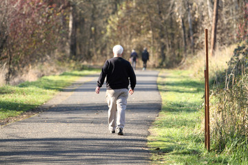 Elderly man taking a walk in a park on a sunny day.