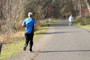 Fototapeta premium Male runner on the path at a park on a sunny day.