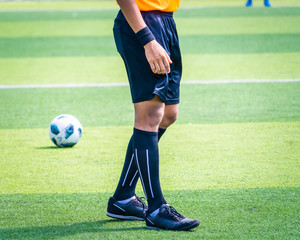 Soccer football referee leg and foot on a soccer competition field stadium with yellow shirt