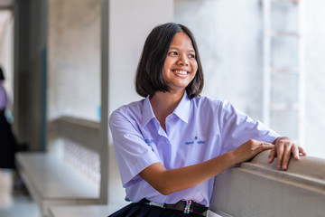 A smiling Asian female high school student in white uniform.