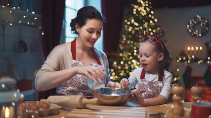 Merry Christmas and Happy Holidays. Family preparation holiday food. Mother and daughter cooking cookies.