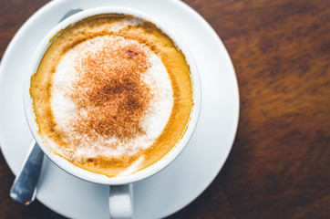 close up modern hot black coffee the cappuccino on wood background with coffee bubble foam pattern and texture in white cup looking and feel so delicious on glasses table in coffee shop.