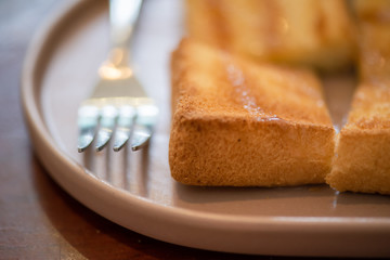 Butter baked bread topped with delicious milk and sugar by using a fork to eat in retro coffee shop.