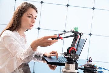 A young woman writes an algorithm for the robot arm. Science Research Laboratory for Robotic Arm Model. Computer Laboratory