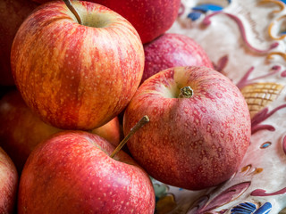 Big plate with red and yellow ripe apples on a wooden vintage table, close-up