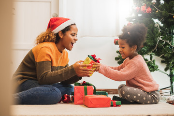 Young black african mother giving Christmas present gift box to her daughter, merry christmas and happy new year concept