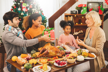 Thanksgiving family on table, giving present box to grandmother