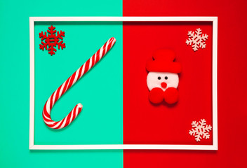 Christmas composition with decorative snowman, lollipop and snowflakes on red and green background with white frame. Winter holiday concept.