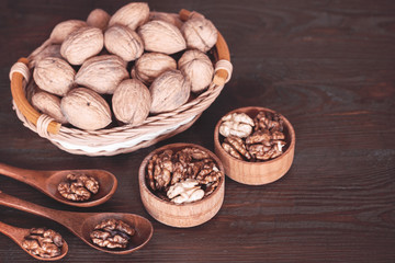 background with walnuts. walnuts in a wicker basket, wooden cups and spoons closeup.
