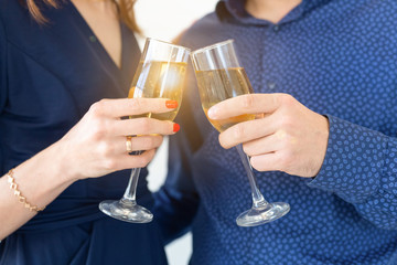 Close-up of man and woman celebrating Christmas or New Year eve party with glasses of champagne.