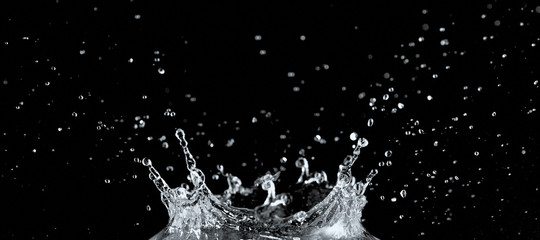 Water splash and drops isolated on black background.