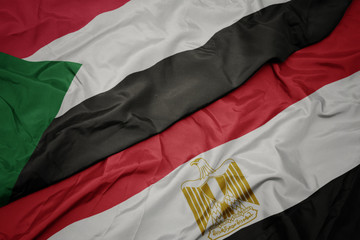 waving colorful flag of egypt and national flag of sudan.