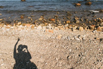 shadow of girl holding smartphone by the sea