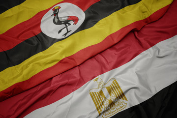 waving colorful flag of egypt and national flag of uganda.