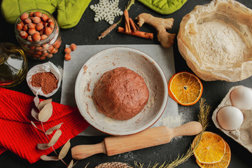 The process of making christmas cookies. Girl hands make the dough. Ingredients for baking a pie: flour, confectionery, dishes, kitchen utensils, spruce cookies figure on a dark background.Christmas g