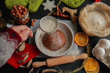 The process of making christmas cookies. Girl hands make the dough. Ingredients for baking a pie: flour, confectionery, dishes, kitchen utensils, spruce cookies figure on a dark background.Christmas g