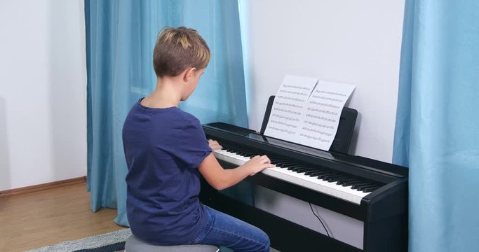 Cute little boy playing piano in room