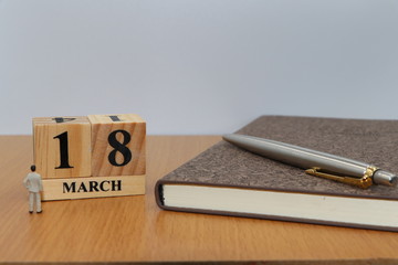 March  18, a calendar photo from the wood The table top consists of a book and pen that is ready to use. White background