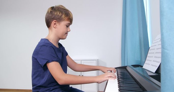 Cute little boy playing piano in room