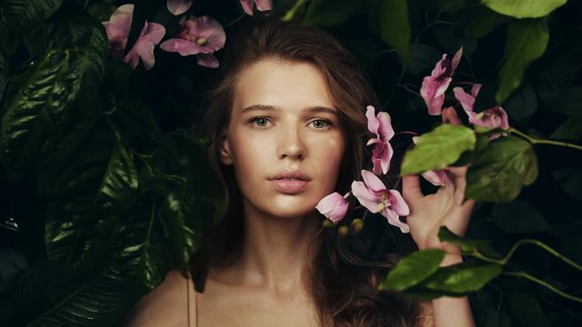 Beautiful girl among the plants and flowers of the archidea. Natural cosmetics and skin care. Exotic flower. Girl in jungle. Perfume Advertising.